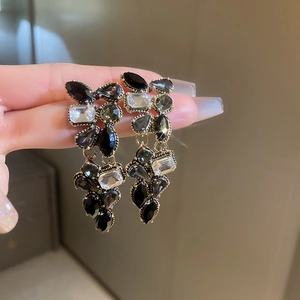 Close-up of black and clear teardrop earrings with a luxurious golden metal finish