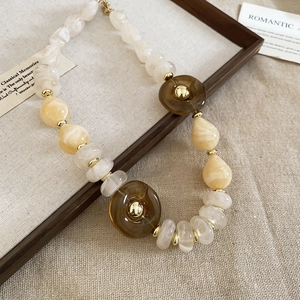 Detail of acrylic irregular beads necklace with gold spacers on vintage wooden frame