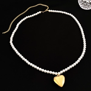 Vintage metal heart pearl body chain and belt accessory for women on a black background