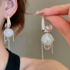 Detail of silver pearl drop earrings featuring chain fringe and elegant metal mesh wrap