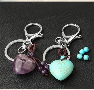 Detail of heart crystal keychains with amethyst and turquoise stones on black leather