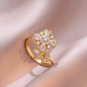 Bague dorée trèfle rotatif élégante avec zirconiums sur fond de soie couleur champagne
