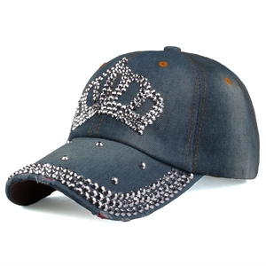 Detailed close-up of crown rhinestone and rivet studs on blue washed denim baseball cap