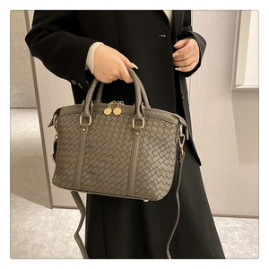 Détail de la texture en cuir tressé gris sur le sac seau avec fermeture éclair dorée