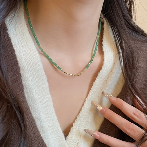 Elegant beaded necklace featuring green jade beads and a gold pony pendant on a model