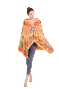 Detail of vibrant orange microfiber beach poncho with Bohemian sun and floral patterns