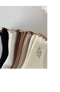 Detailed macro view of ribbed cotton socks with floral embroidery and ruffled edge