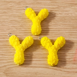 Detail of yellow resin letter Y pendants with 3D rose texture and silver metal loops