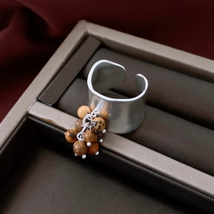 Close-up of silver irregular pleated wide ring with brown mineral bead pendant detail