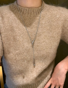 Detail of silver water-drop pendant on an adjustable Y-shaped necklace over a knit sweater