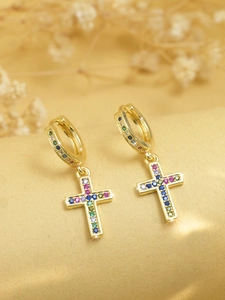 Close-up of golden hoop earrings featuring cross pendants with rainbow zircon stones