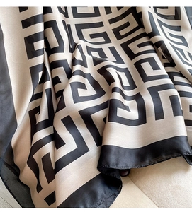 Detailed view of beige silk scarf showing black Greek key pattern and soft fabric texture