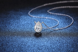 Macro detail of pear-shaped moissanite pendant with halo setting in silver