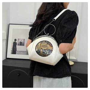 Detail of white leather shell bag with gold round handle and floral elephant relief