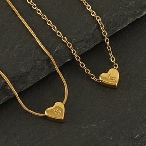 Close-up of 18K gold stainless steel heart pendant necklaces with letters B and C