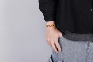 Close-up of gold-plated thick chain bracelet with embossed links on model wrist