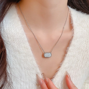Detailed view of silver oval pendant with white glitter stone on dainty chain