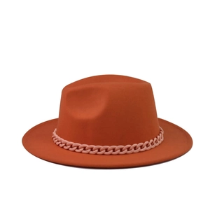 Detail of a bright orange flat top wool felt hat with a decorative pink chain detail