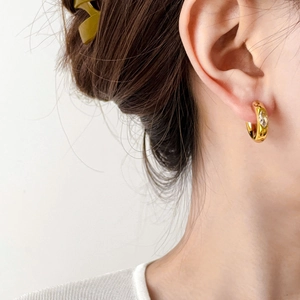 Close-up of thick gold hoop earring with a single sparkling zircon stone on ear