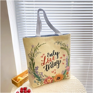 Detail of embroidered canvas tote bag with floral wreath and blue striped handles