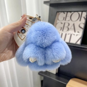 Macro detail of a soft light blue faux fur rabbit keychain with a golden metal hook