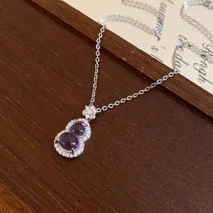 Macro shot of a purple hulu pendant with zircon stones on a silver chain necklace