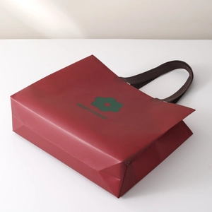Red non-woven tote bag with green floral pattern and New Vogue text for retail shopping