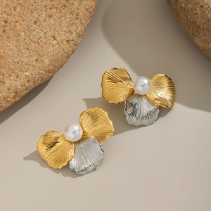 Elegant two-tone gold and silver floral stud earrings with white pearls on a stone background