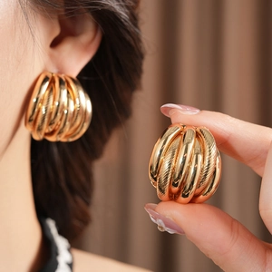 Macro view of gold layered hoop earrings showing C-shape design and brushed metal texture