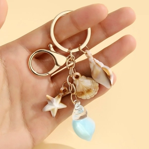 Detail of beach themed keychain with conch starfish shell and blue teardrop charm