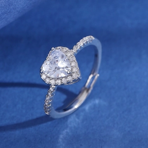 Macro detail of silver heart-shaped clear zircon ring with pavé side stones on blue texture