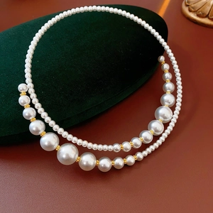 Double-layer pearl choker with white faux pearls and gold spacers on green velvet