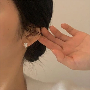 Close-up of 925 sterling silver bow earrings with pearl and zircon on model ear