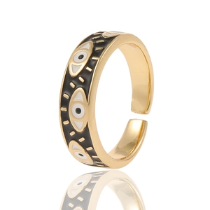 Close-up of golden adjustable open ring with black enamel evil eye pattern and white dots