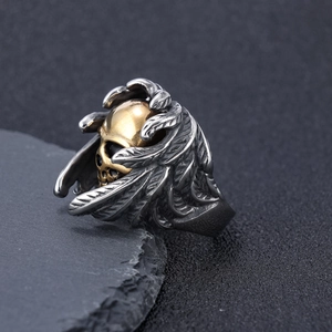 Macro de la bague gothique punk avec crâne doré et détails de plumes en argent vieilli
