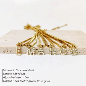 Detalle del colgante de letra con perla y cadena box en acero bañado en oro de 14K