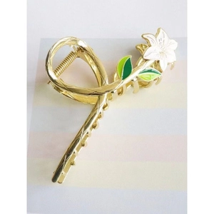 Detail of golden metal hair claw clip featuring white lily flowers and green leaves