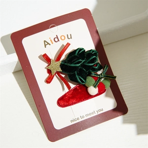 Close-up of green velvet Christmas tree hair clip with golden star and red bow detail
