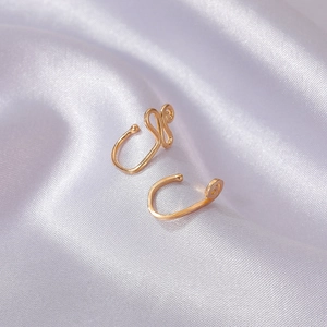 Punk style gold U-shaped non-piercing nose clips on elegant white silk background
