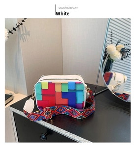 Detailed view of white crossbody bag with pixel patterns and wide ethnic style strap