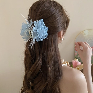 Detail der blauen Organza-Blumen-Haarklammer mit weißen Federn und Perlen im Haar