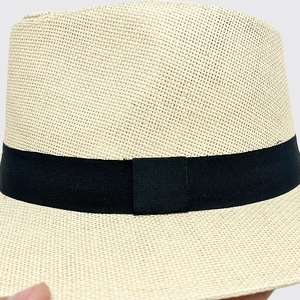 Detailed close-up of woven paper straw texture and black grosgrain ribbon on sun hat
