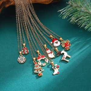 Golden Christmas necklace set with enamel charms of trees and reindeer on green background