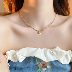 Detail of colorful beaded necklace with a golden butterfly pendant on model in warm light