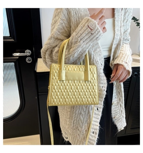 Detail of bright yellow quilted tote bag with teardrop stitching and faux leather finish