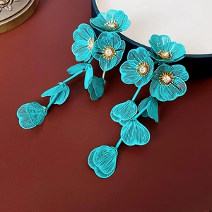 Gros plan sur des boucles d'oreilles fleurs tressées bleues avec strass brillants
