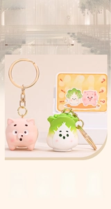Close-up of cute cartoon pig and cabbage resin pendants with golden keychains