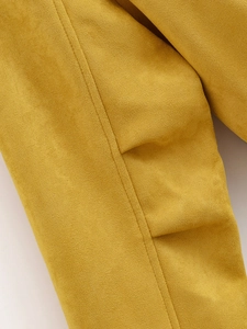 Detailed close-up of mustard yellow suede fabric texture with clean stitching lines