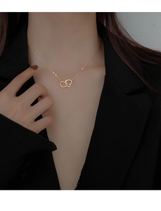 Close-up of a double heart interlocking pendant necklace in gold on a female model