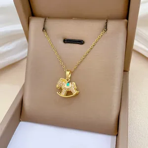 Detailed view of rocking horse pendant with white zircons on a gold necklace in jewelry box